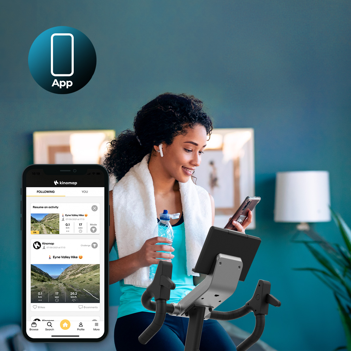 Una giovane donna su una cyclette tiene una borraccia e uno smartphone con un'app fitness.