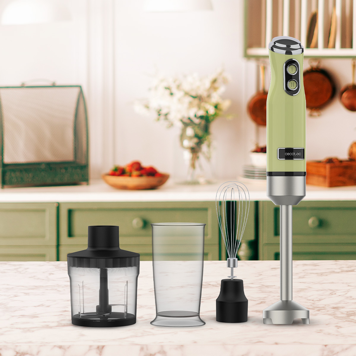 Batidora de mano verde pastel con accesorios en una encimera de mármol.