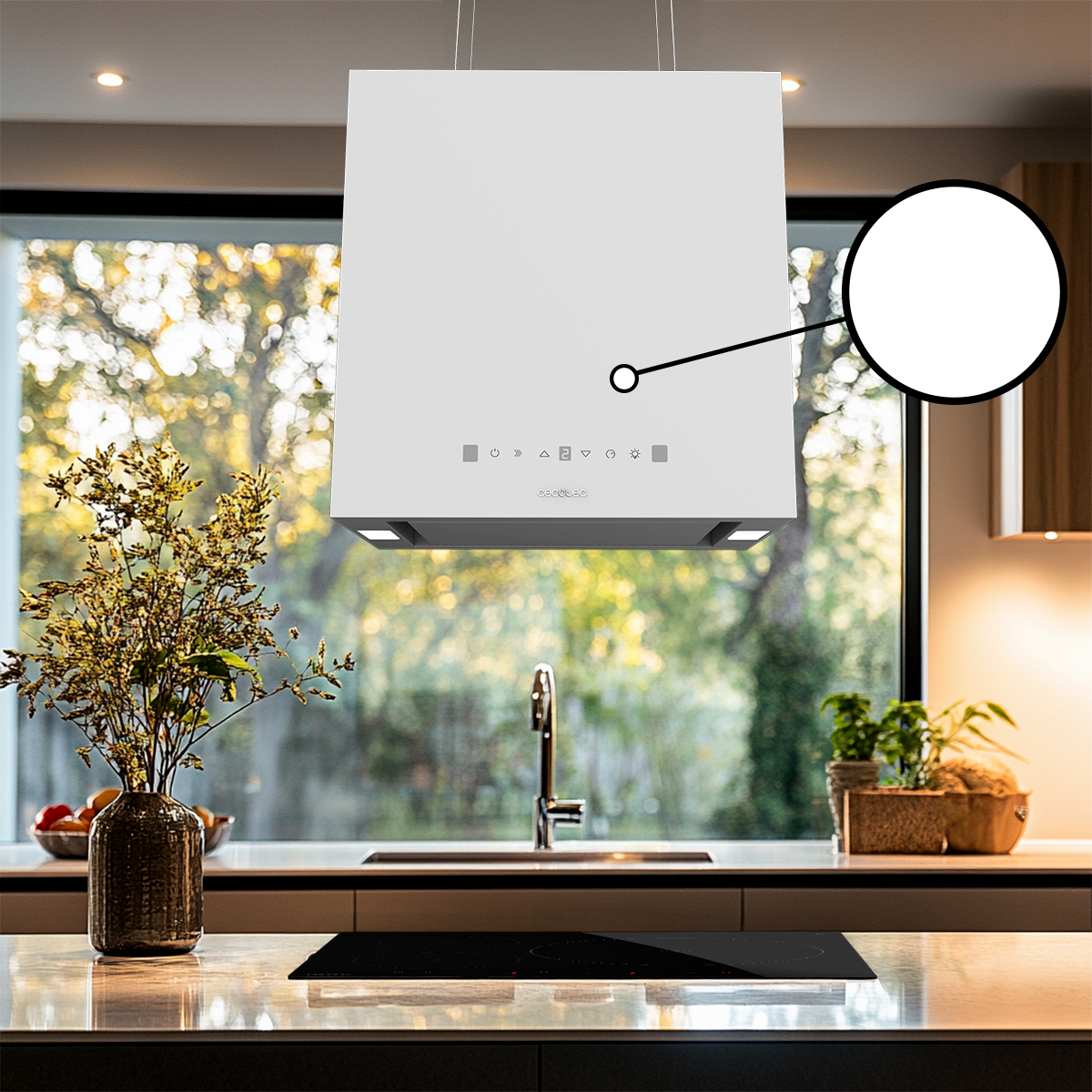 Campana extractora blanca sobre una isla de cocina con placa de inducción y plantas de fondo.