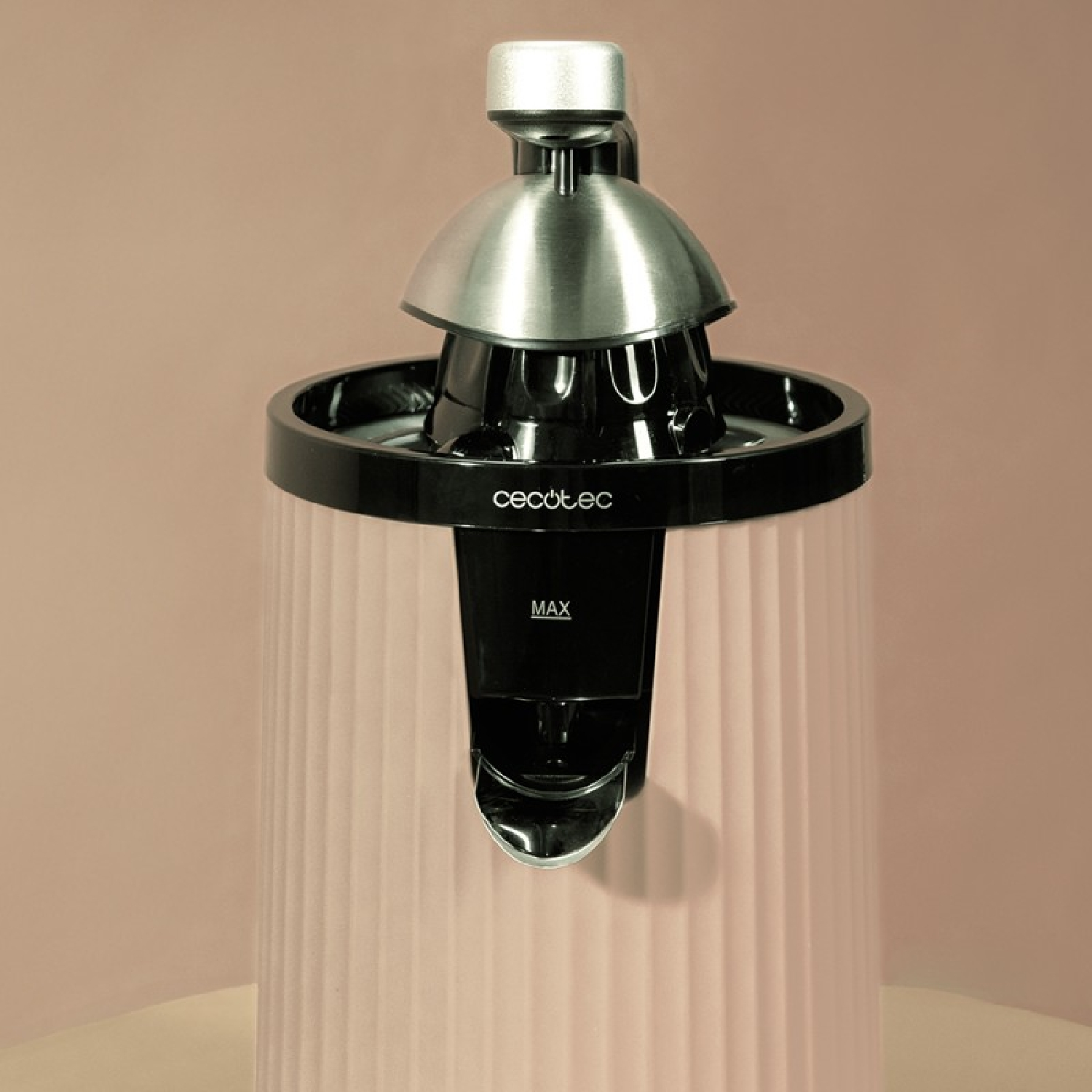 Un estrattore di succo Cecotec rosa con bordo nero e cono argento su sfondo beige.