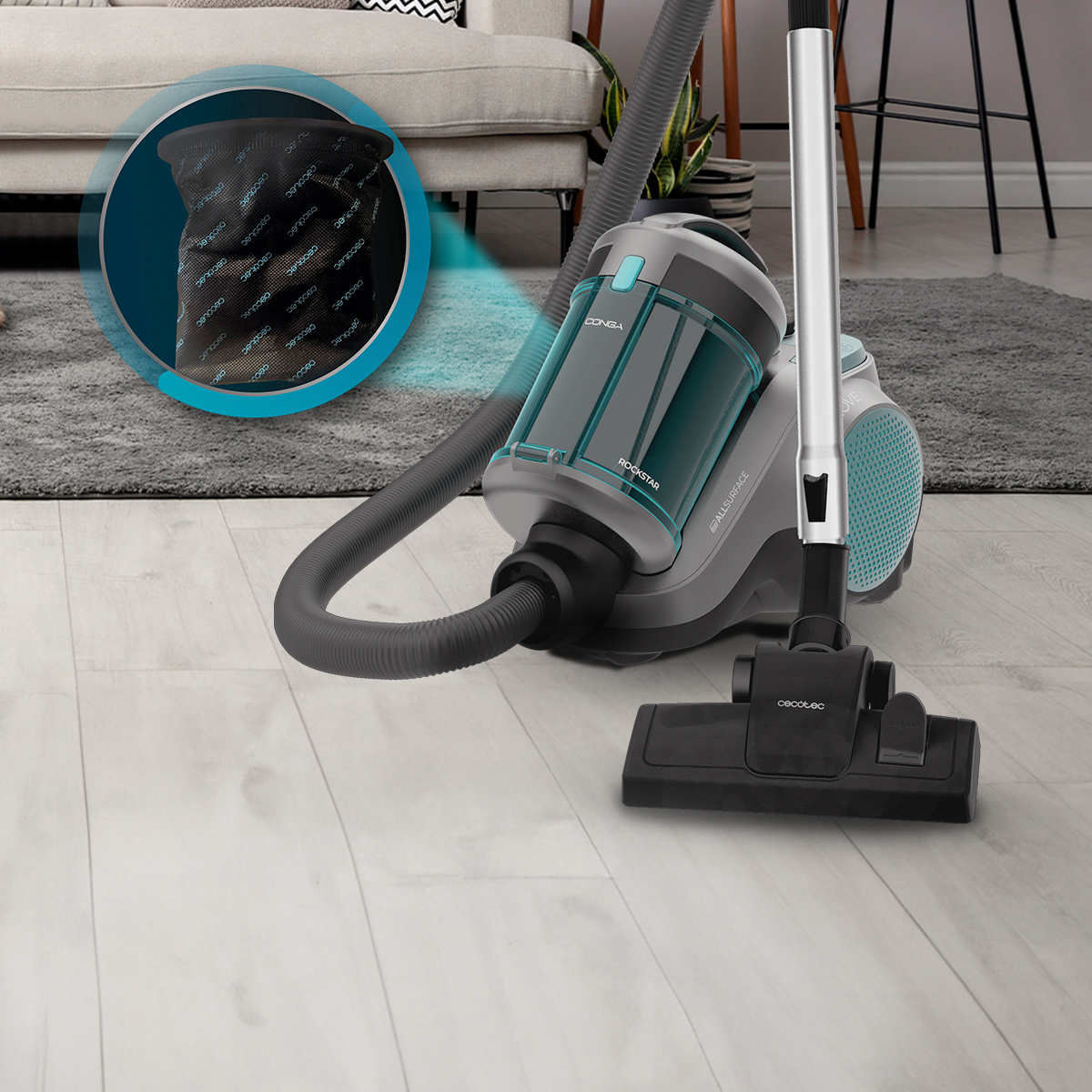 Aspiradora de trineo gris y turquesa en suelo de madera con vista ampliada de su bolsa.