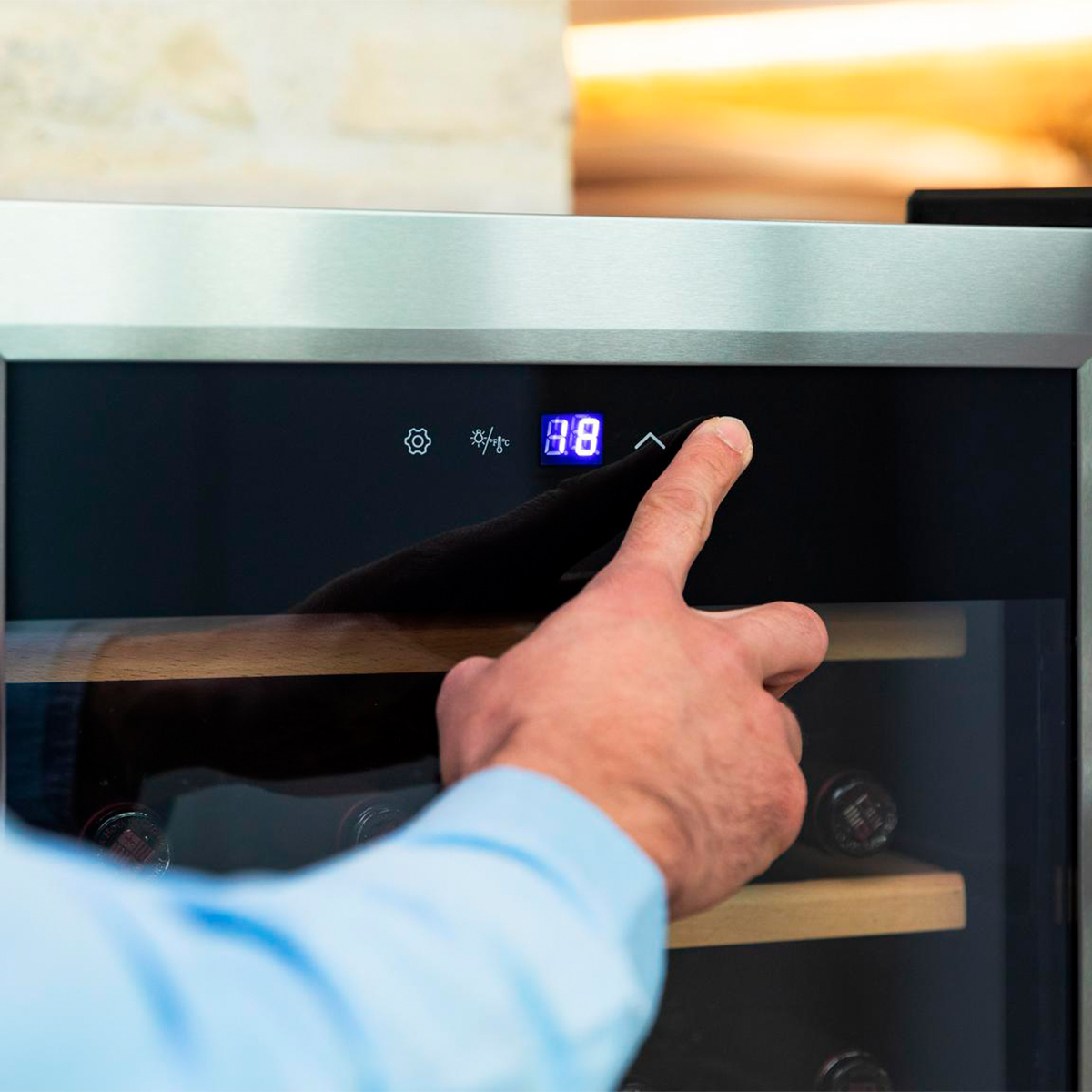 Una mano tocca il pannello di controllo digitale di una cantinetta per vini.