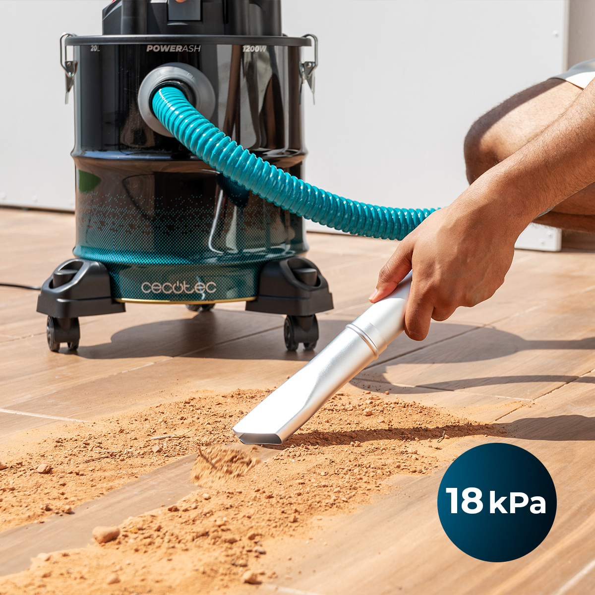 Una persona aspira lo sporco fine da un pavimento in legno con un aspiracenere blu.