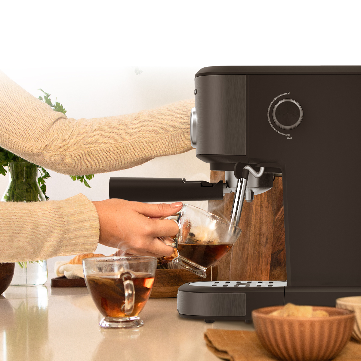 Una persona sirve café de una cafetera negra en una taza sobre una encimera brillante.