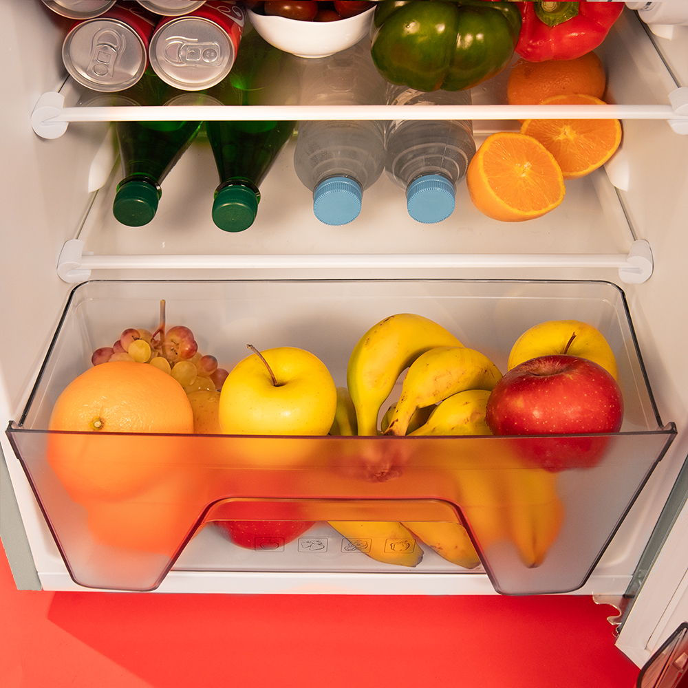 Un refrigerador abierto lleno de frutas frescas, verduras, bebidas enlatadas y botellas.