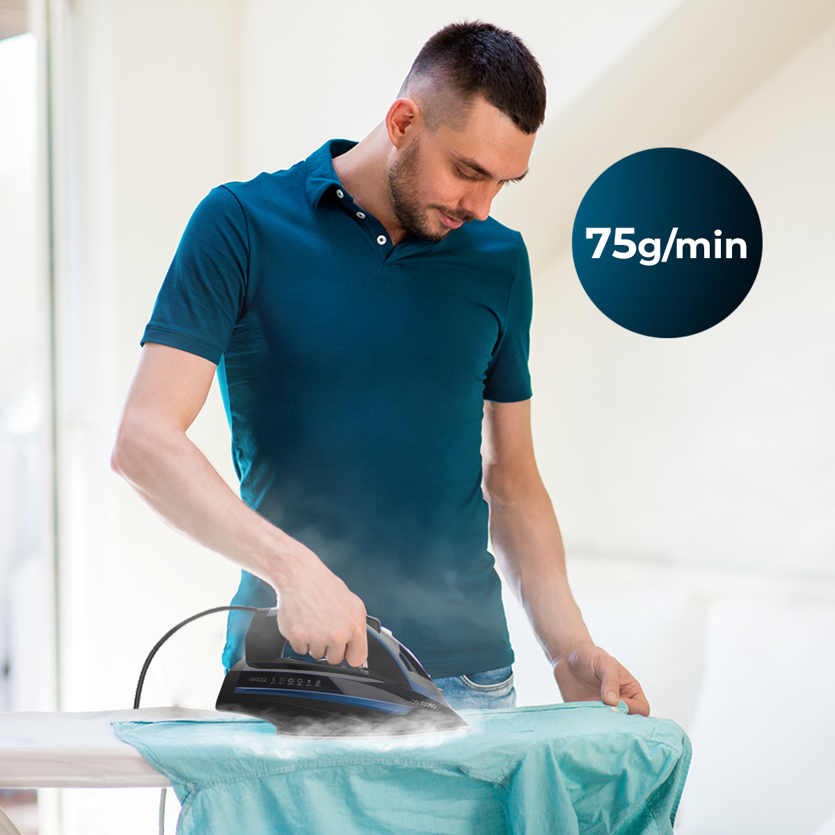 Un uomo in polo blu stira una camicia con un ferro da stiro a vapore nero, emettendo 75g/min di vapore.