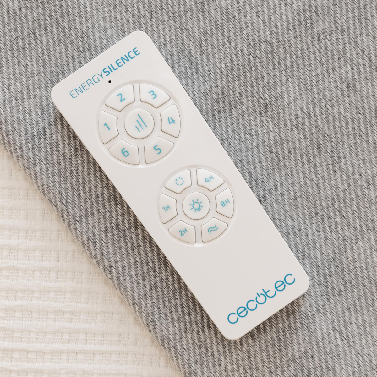 Un telecomando bianco Cecotec EnergySilence su sfondo in tessuto grigio.