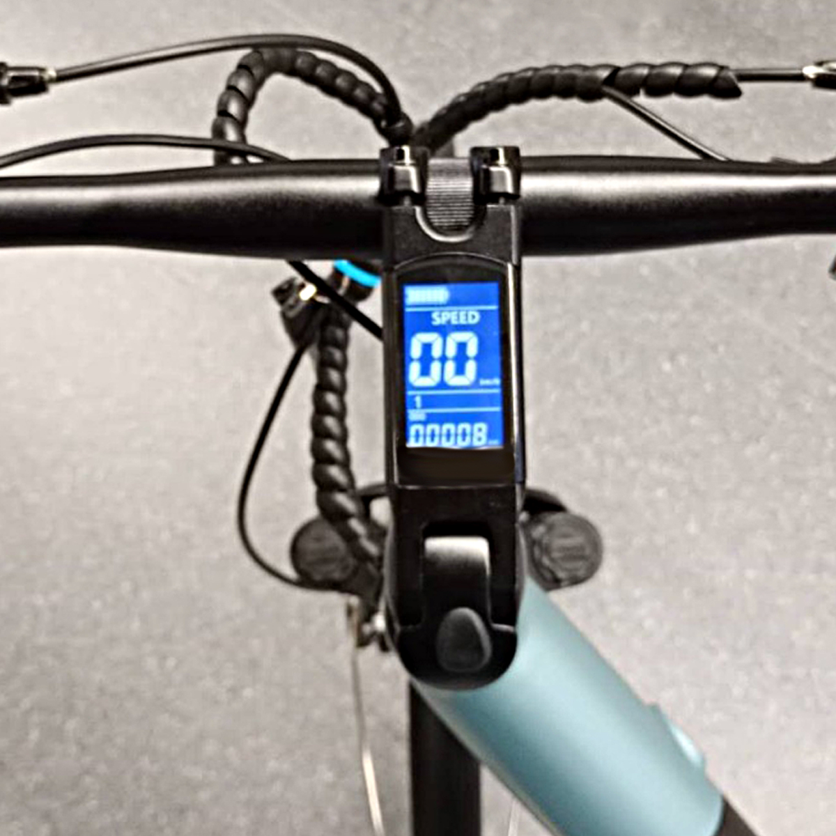 Manillar de bicicleta eléctrica con pantalla digital azul central que muestra velocidad y kilometraje.