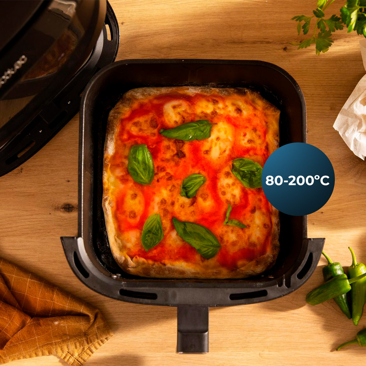 Pizza fresca con salsa di pomodoro e basilico in una friggitrice ad aria su legno.