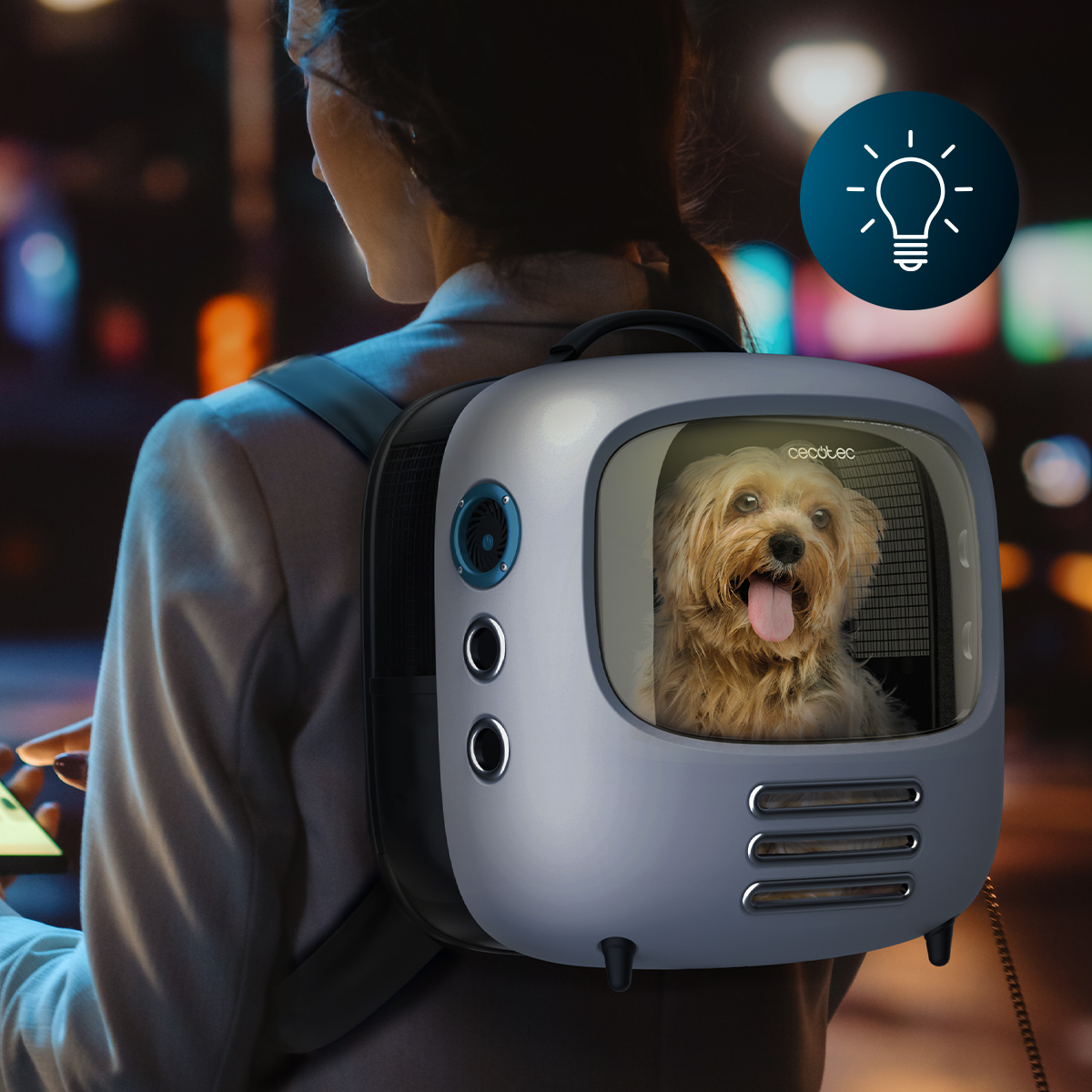 Kobieta niesie szary plecak dla zwierzaka z małym terrierm wyglądającym z wystawionym językiem.