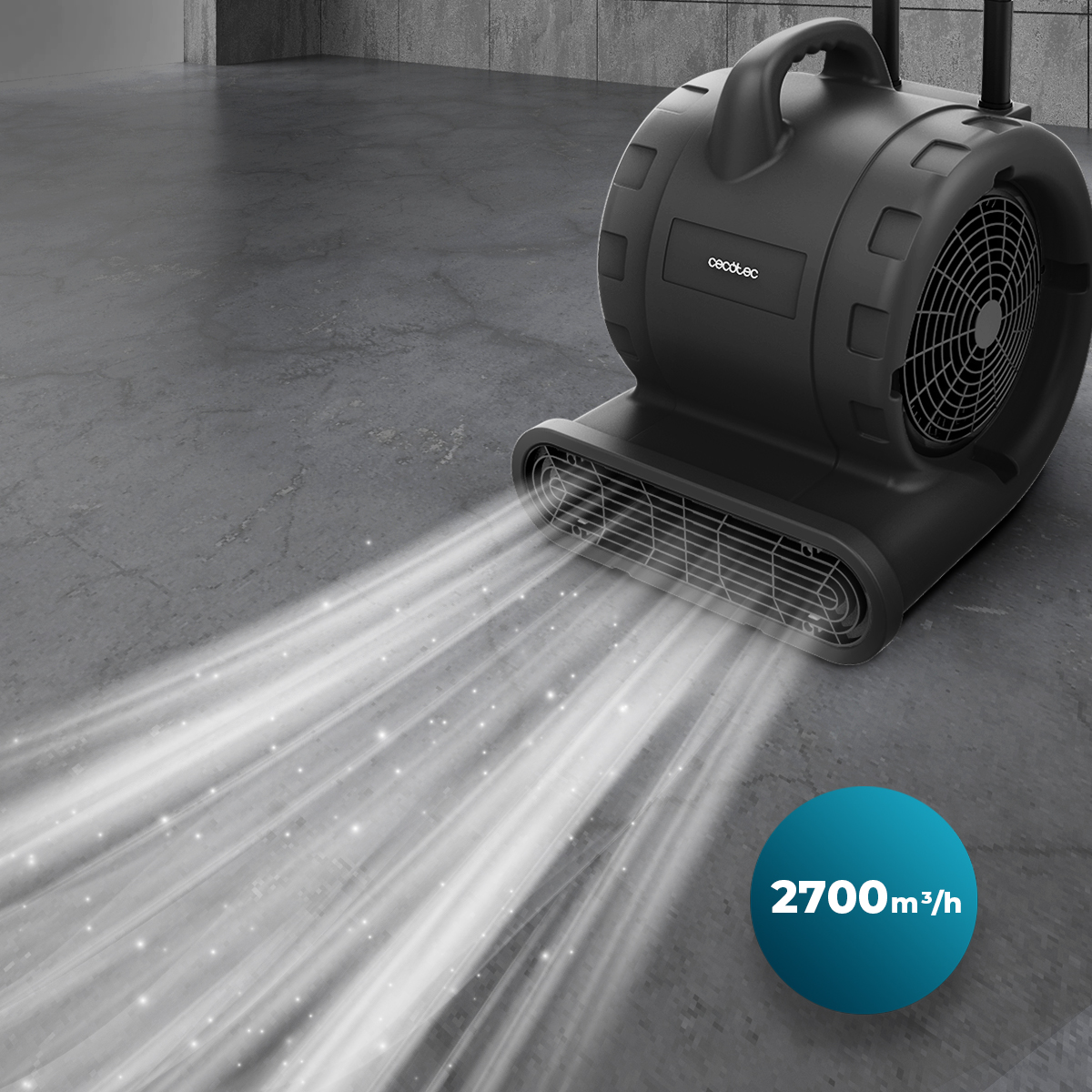 Un ventilador industrial negro sopla aire potente sobre un suelo de hormigón gris, con una insignia azul.
