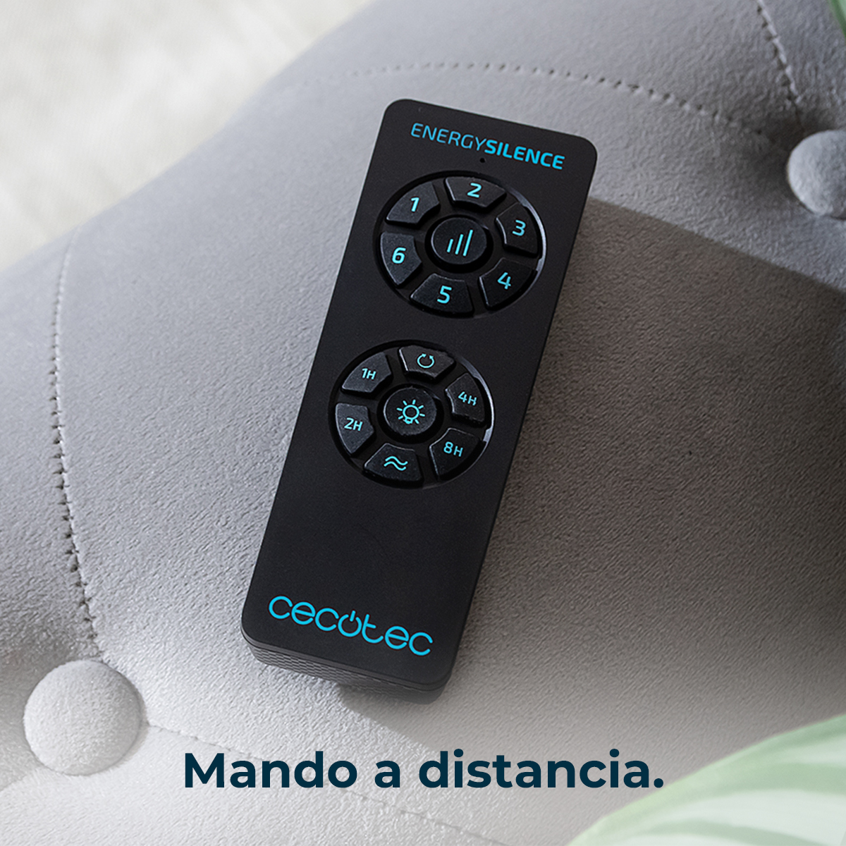 Un mando a distancia negro Cecotec EnergySilence con botones azules descansa sobre un sofá gris.