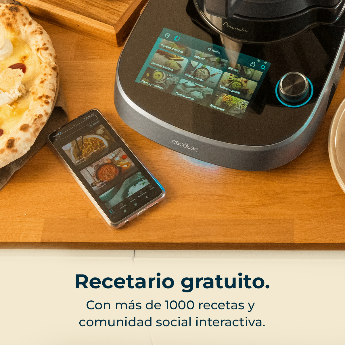 Cocina con robot de cocina Cecotec Mambo, smartphone y pizza en tabla de madera.