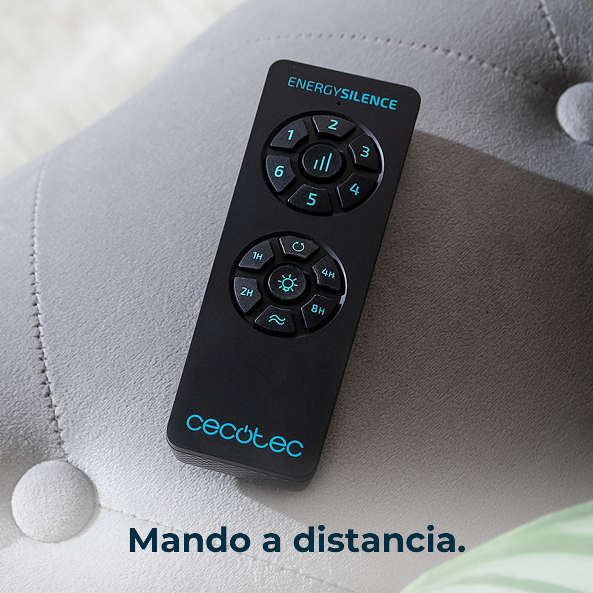 Telecomando nero Cecotec EnergySilence con pulsanti blu su un divano grigio chiaro.