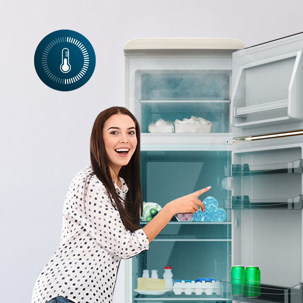 Una mujer sonriente señala el interior de un refrigerador abierto con alimentos y un icono de termómetro.