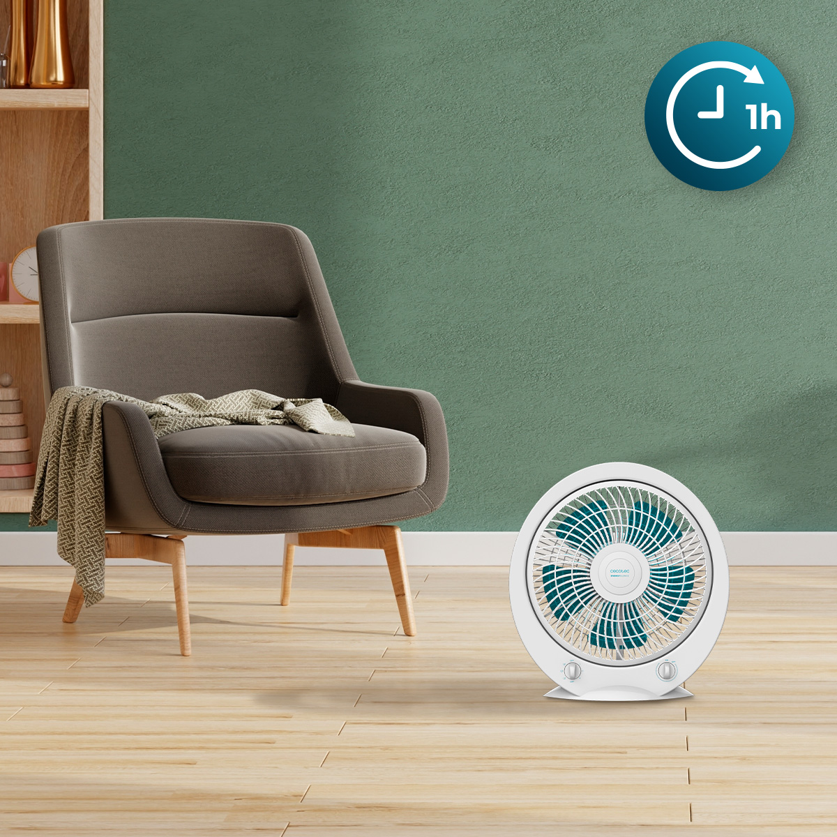 Un ventilatore da tavolo bianco con pale blu è appoggiato su un pavimento in legno davanti a una poltrona verde.