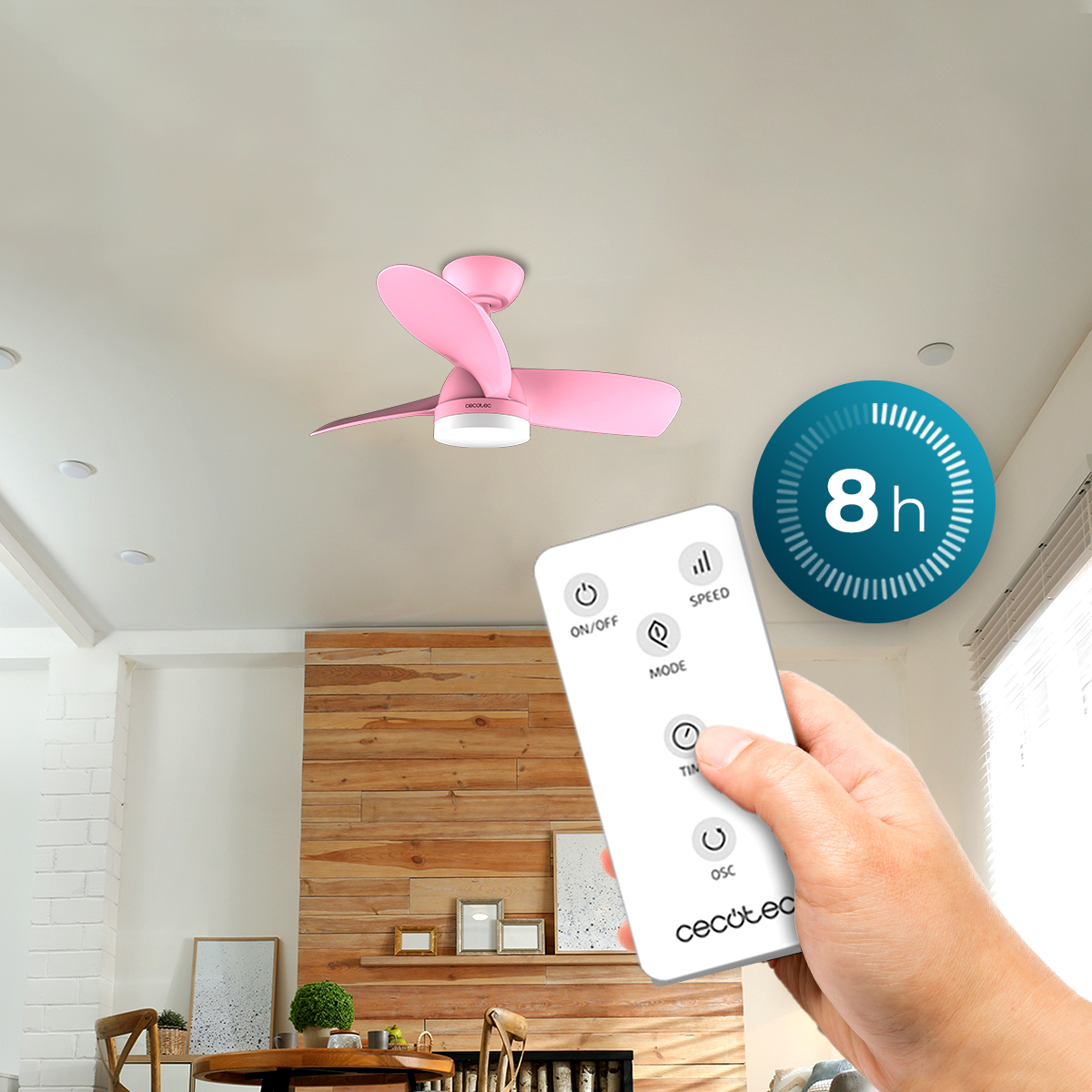 Una mano tiene un telecomando bianco per un ventilatore da soffitto rosa.