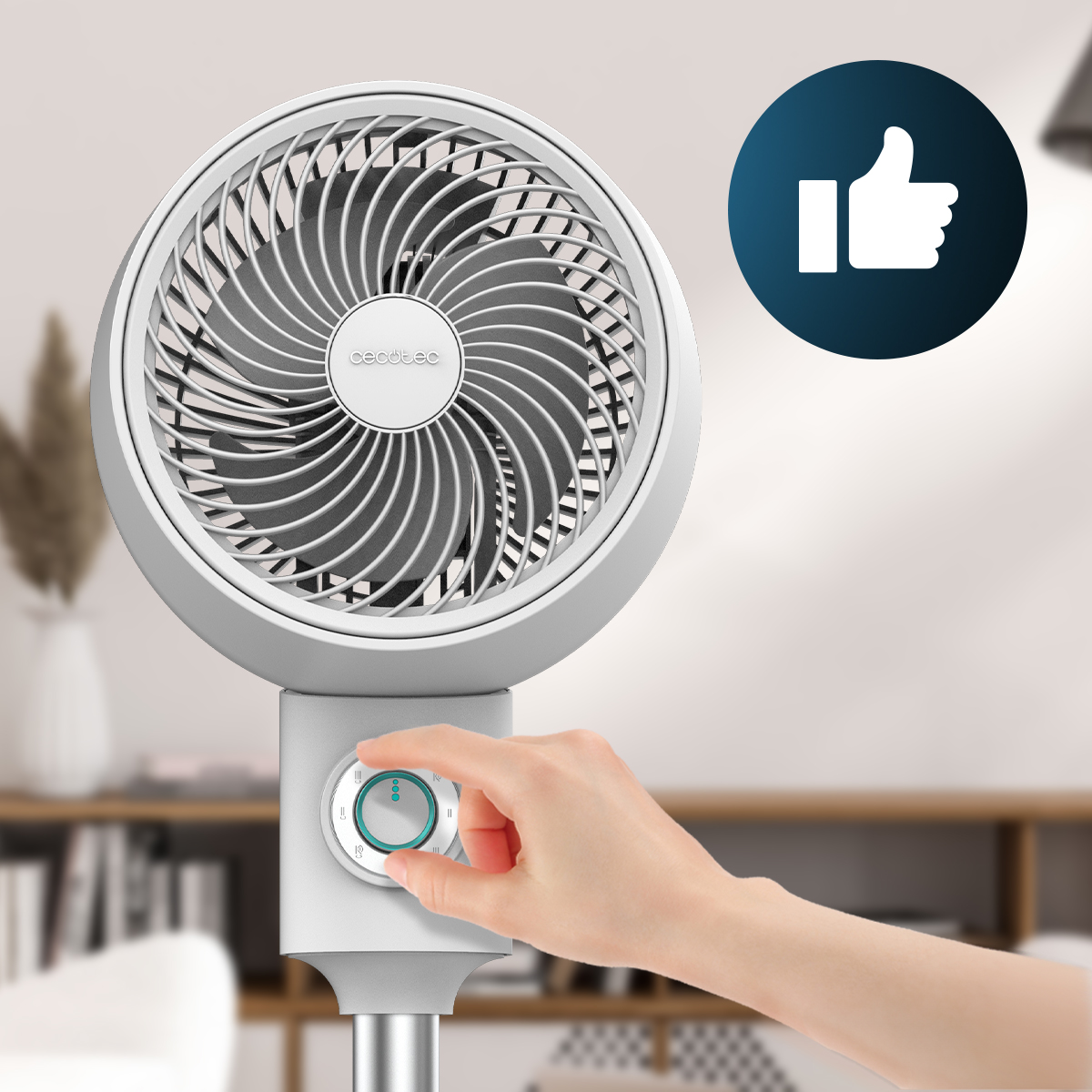 Una mano gira la rueda de un ventilador de pie blanco Cecotec, con un icono de pulgar arriba.