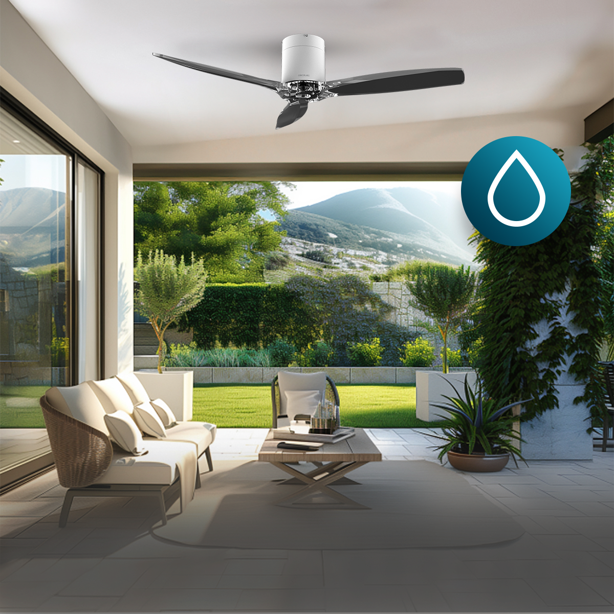 Patio coperto con soffitto bianco, ventilatore, divano bianco, tavolo in legno, piante e vista sulle colline.