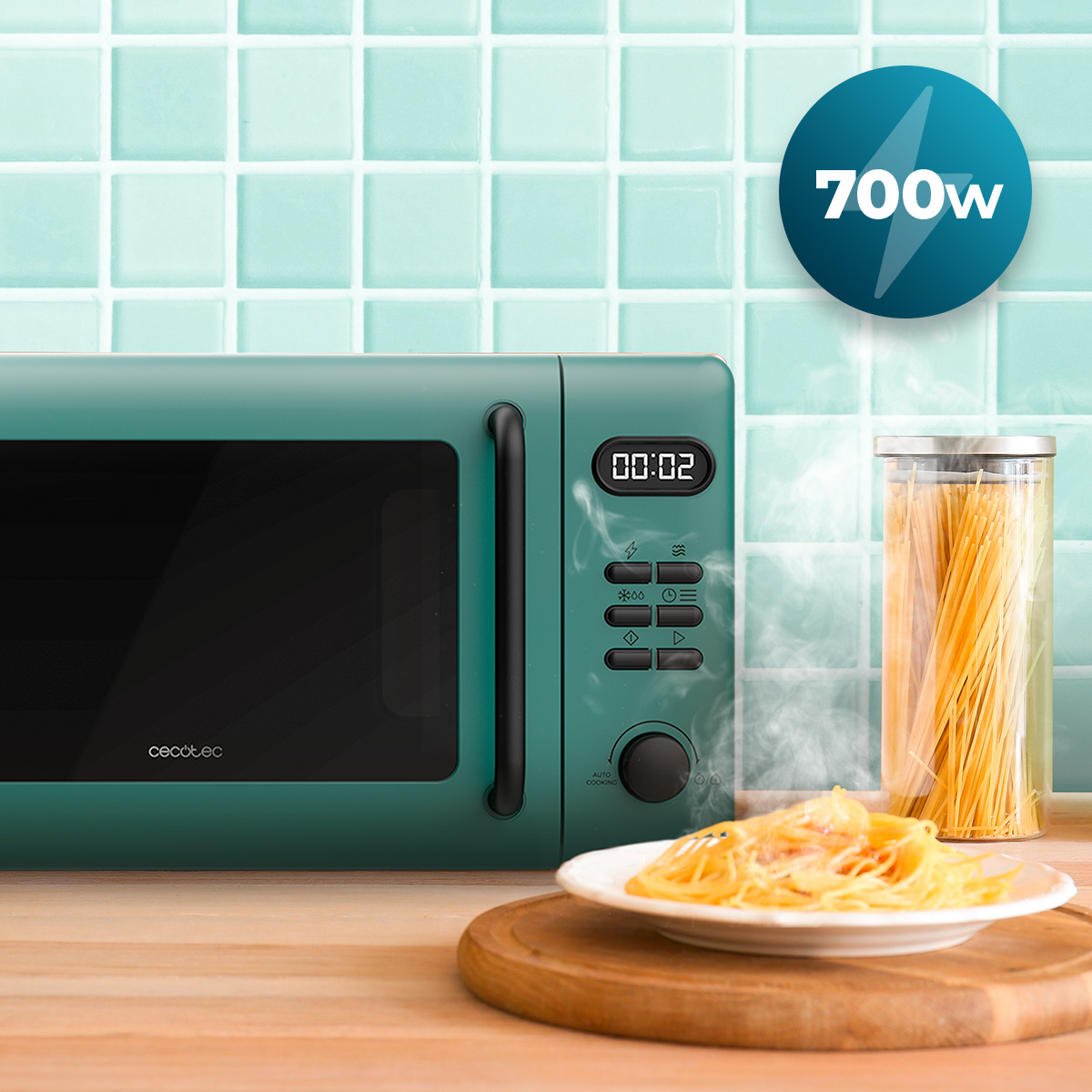 Un microondas verde azulado sobre una encimera de madera con pasta humeante y un tarro de pasta frente a azulejos turquesas.
