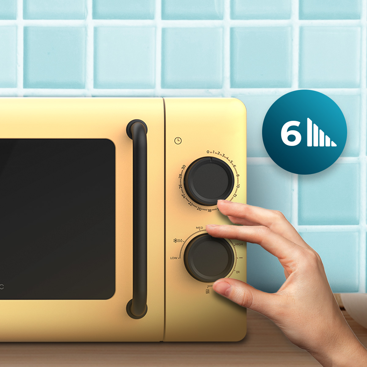 Una mano gira el dial de un microondas retro amarillo contra una pared de azulejos celestes.