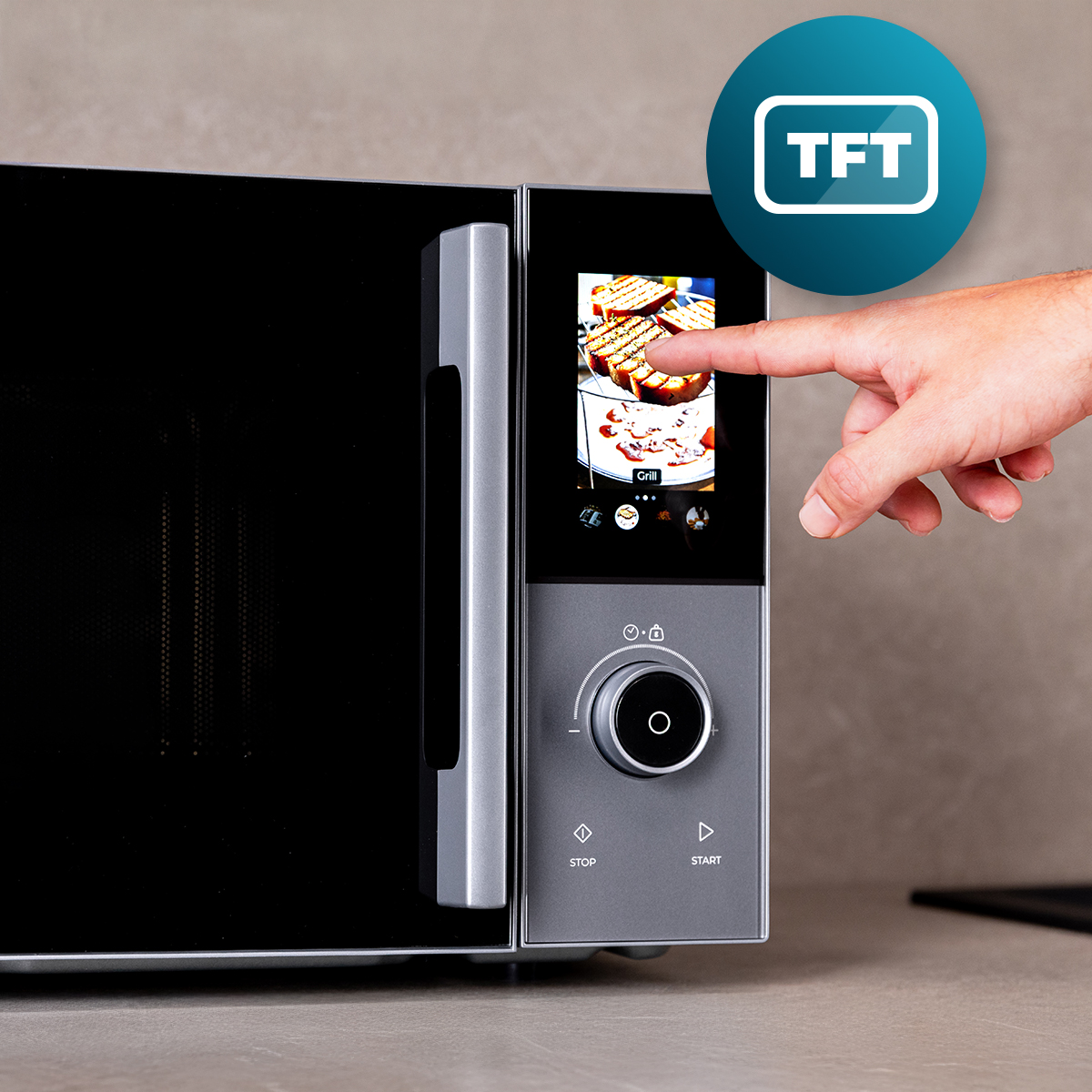 Una mano opera la pantalla táctil TFT de un microondas moderno con perilla y asa.
