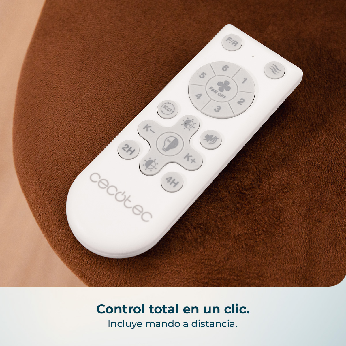 Un mando a distancia blanco de Cecotec con botones grises reposa sobre un cojín marrón.
