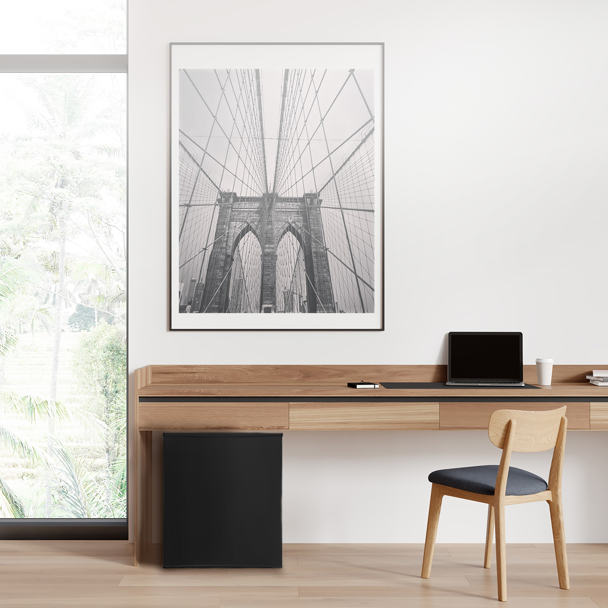 Espacio de trabajo moderno con escritorio de madera, silla, portátil y un cuadro en blanco y negro.