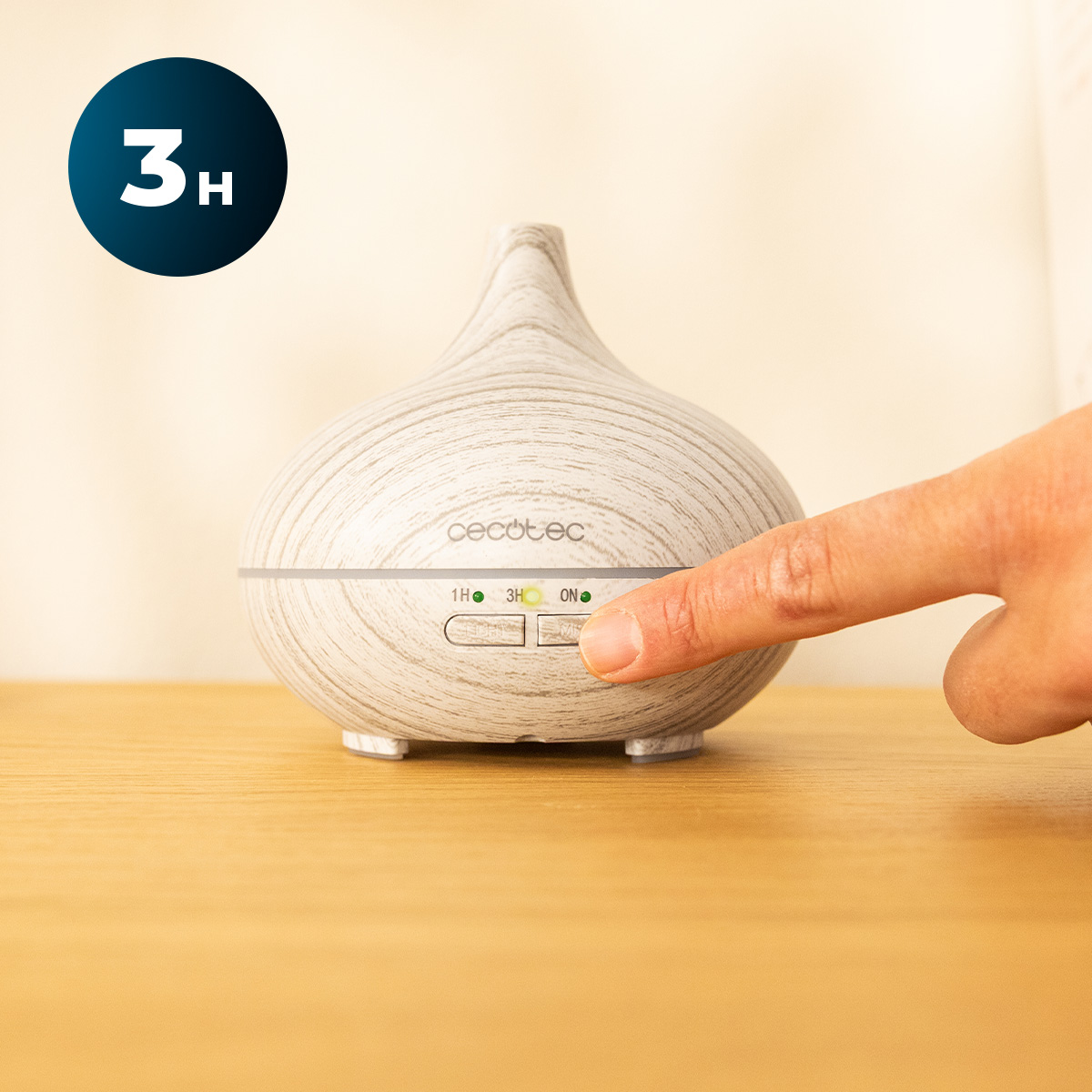 Eine Hand drückt auf einen Holzmuster-Aroma-Diffusor mit Kontrollleuchten auf einem Tisch.