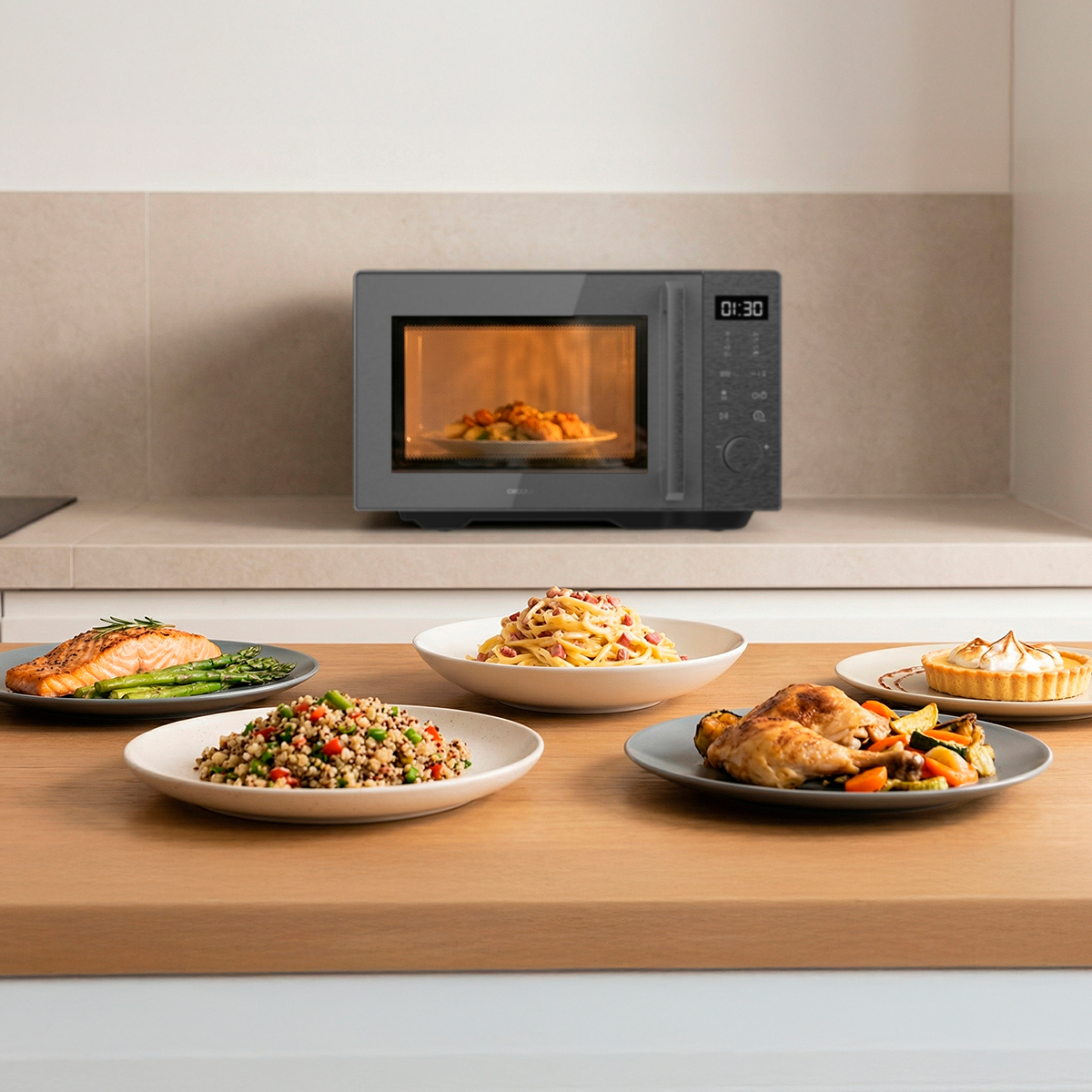 Un microondas moderno sobre la encimera y varios platos con salmón, pasta, pollo y tarta en una mesa de madera.