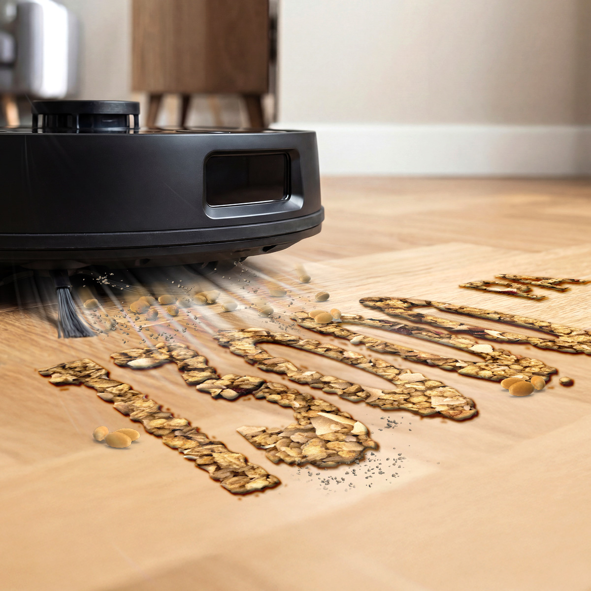 Un robot aspirador negro limpia un suelo de madera cubierto de granos y semillas.