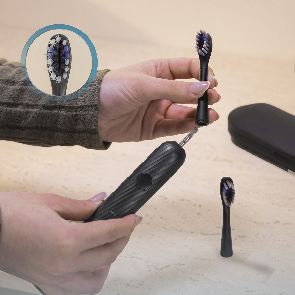 Manos sostienen un cepillo eléctrico negro con cabezal intercambiable y estuche.