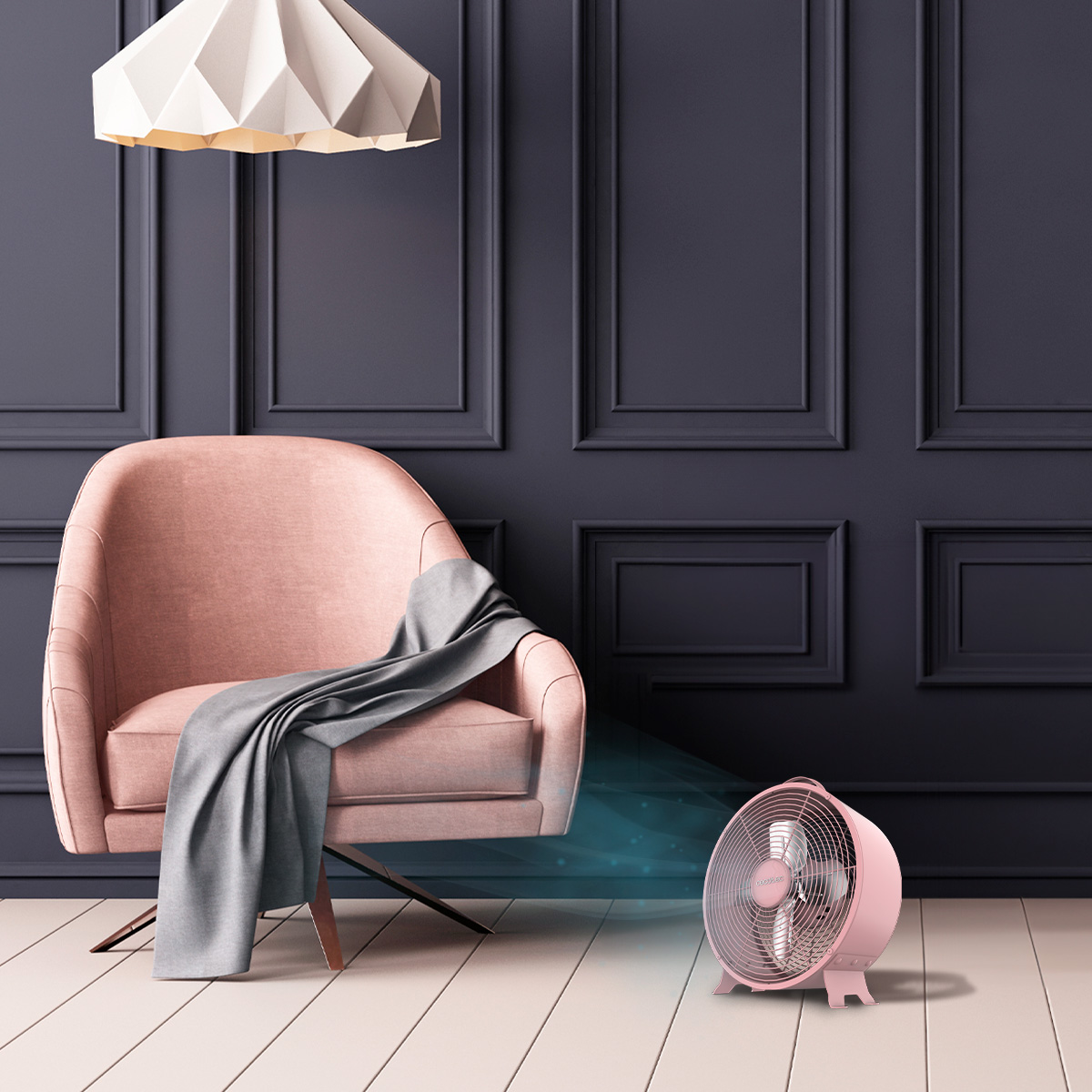 Una poltrona rosa con una coperta grigia davanti a pareti scure, accanto a un piccolo ventilatore rosa.