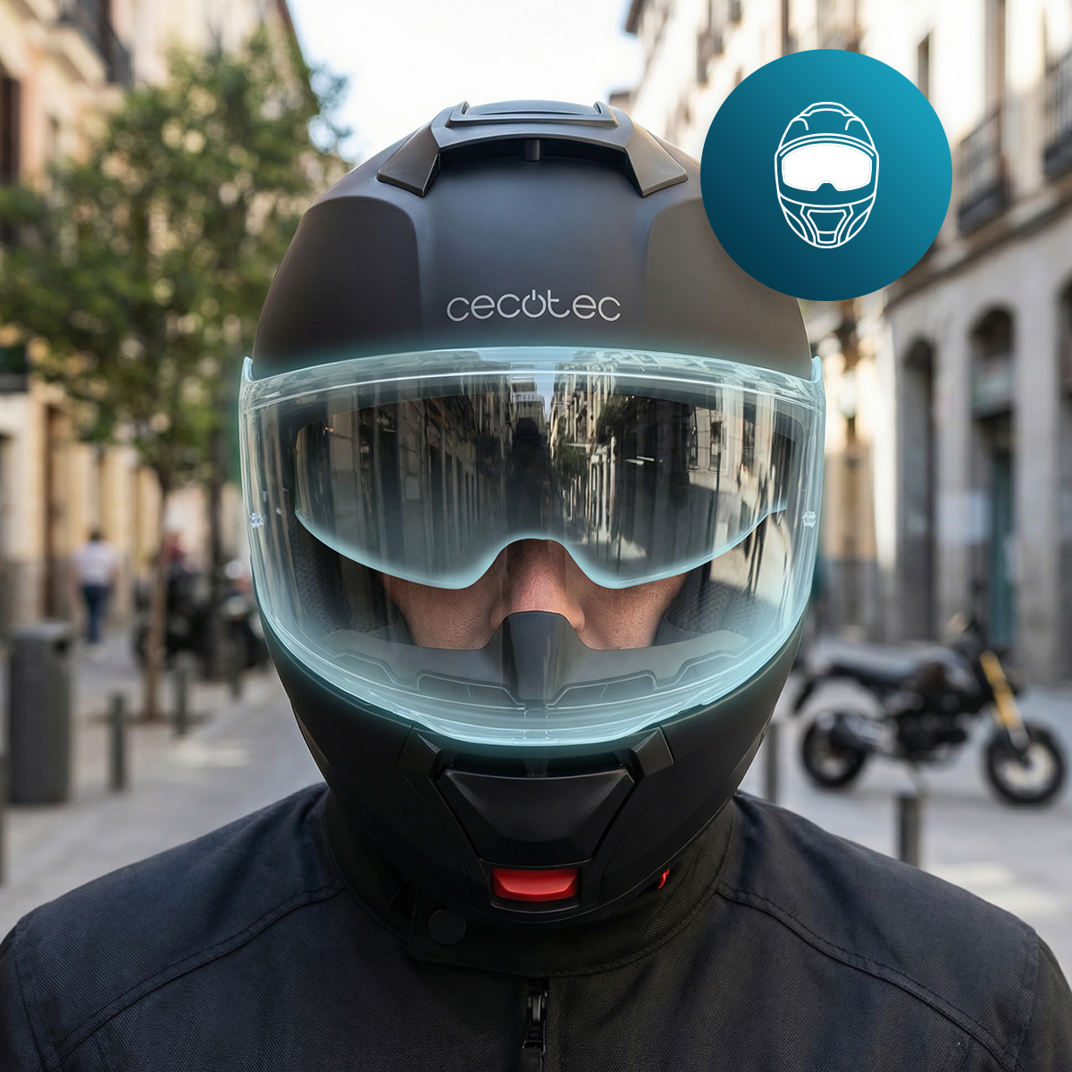 Un casco negro mate Cecotec con visera transparente, sobre un fondo urbano difuminado.