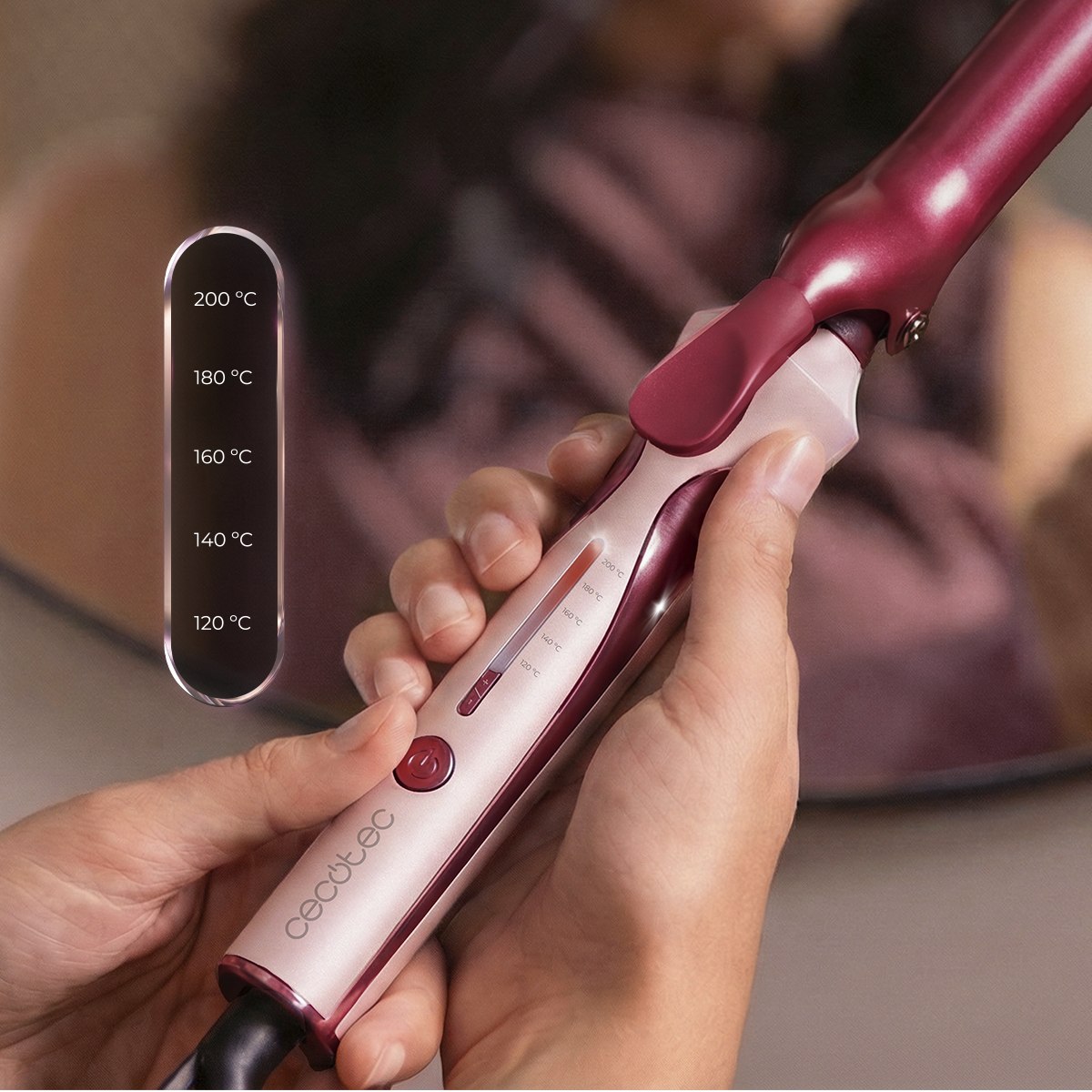 Una persona sostiene un rizador Cecotec rosa y granate, con un recuadro que muestra ajustes de temperatura de 120 C a 200 C.