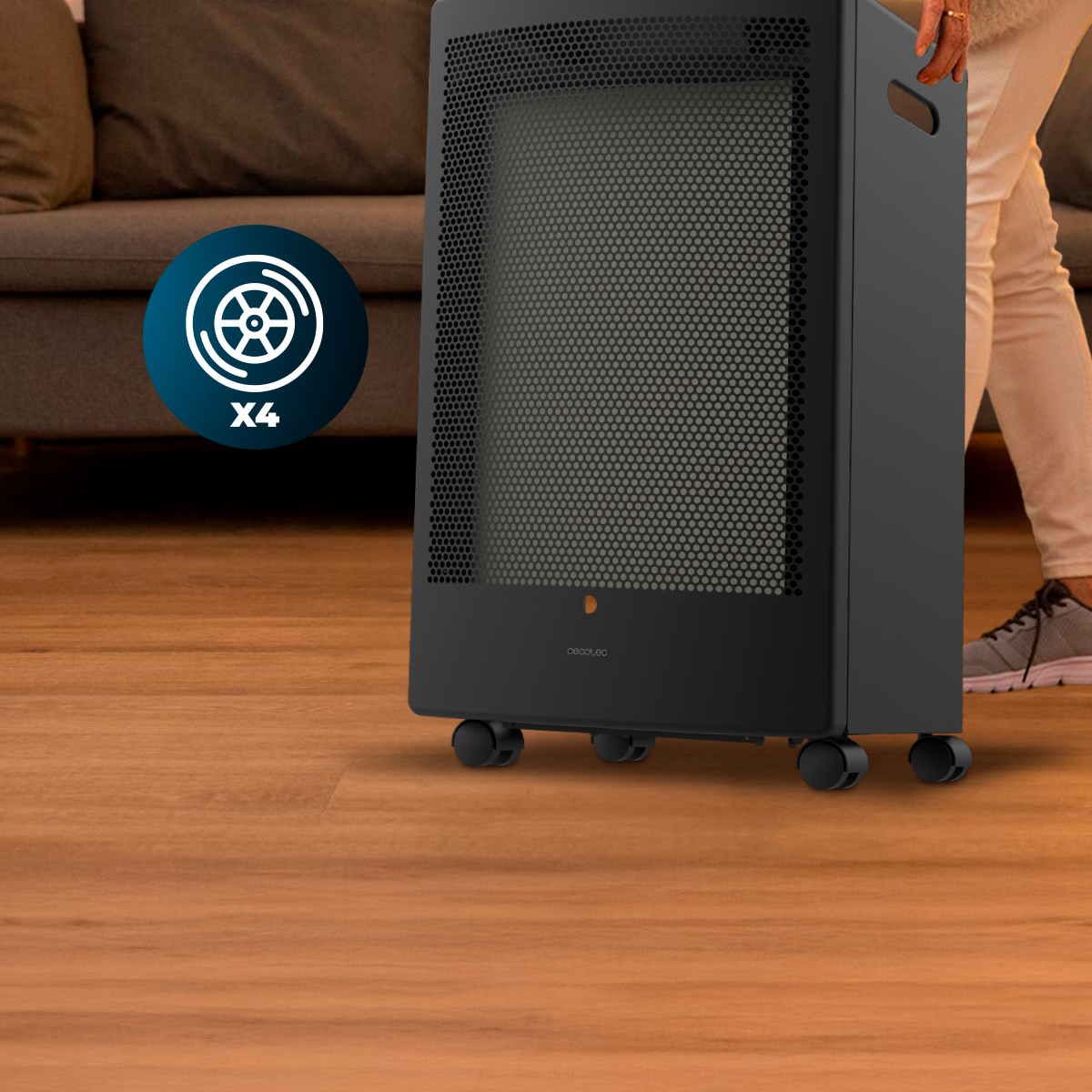 Un calefactor negro con cuatro ruedas sobre suelo de madera, con un sofá al fondo.