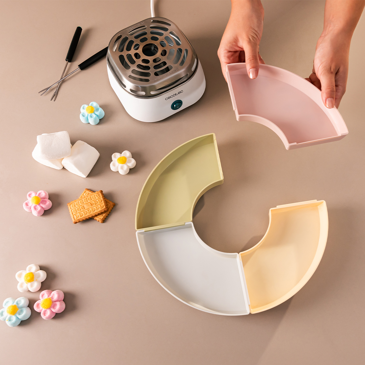 Set per fonduta con scaldavivande, vassoi colorati, marshmallow e biscotti su un tavolo.