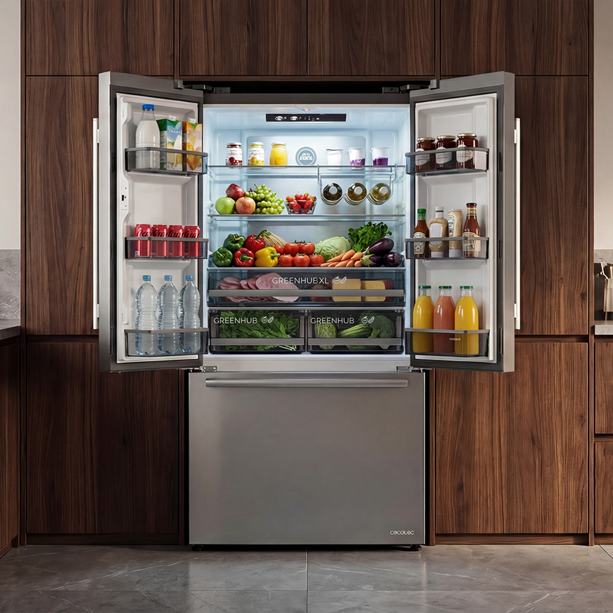 Un refrigerador de acero inoxidable abierto lleno de coloridas frutas, verduras, bebidas y frascos sobre gabinetes de madera.