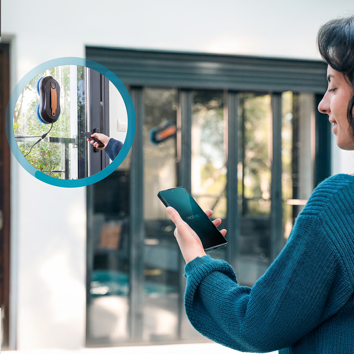 Una donna tiene uno smartphone mentre un robot lavavetri lavora su una finestra sullo sfondo.
