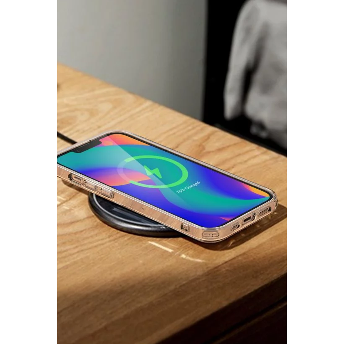 Ahşap bir masa üzerinde yuvarlak bir ped üzerinde kablosuz şarj olan akıllı telefon.