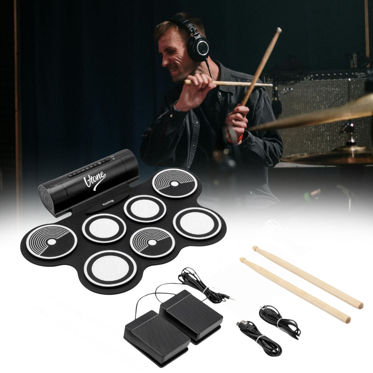 Ein tragbares elektronisches Schlagzeug mit Pads, Pedalen und Drumsticks, im Hintergrund spielt ein Schlagzeuger.
