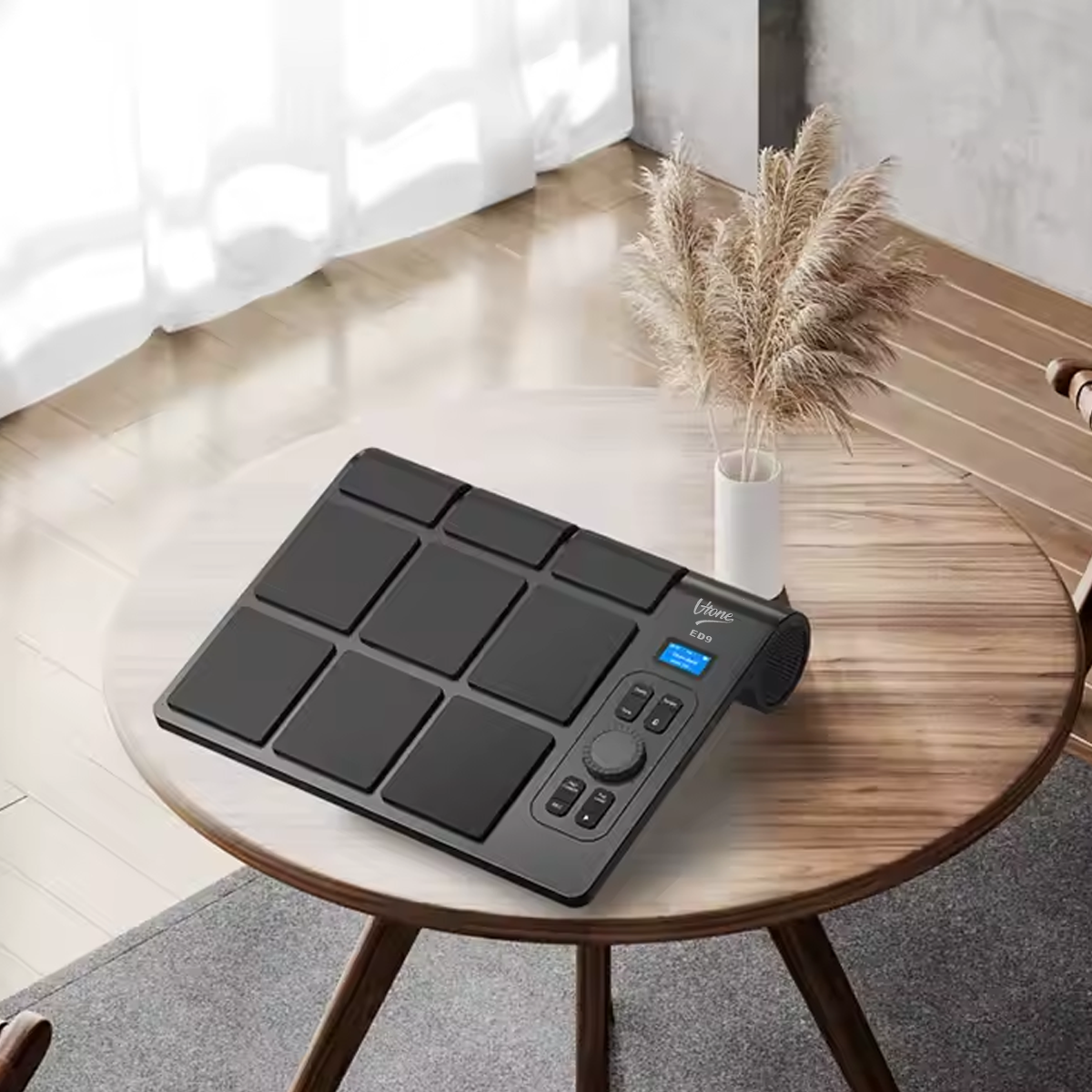 Ein schwarzes elektronisches Schlagzeug-Pad auf einem runden Holztisch in einem hellen Raum.
