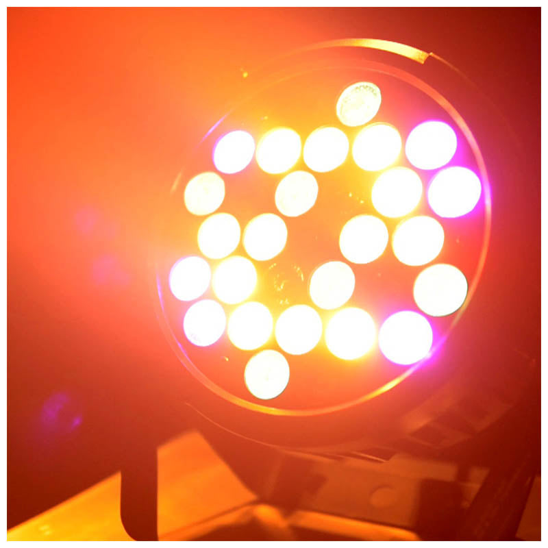 Ein heller runder LED-Strahler leuchtet in kräftigem Orange und Pink.