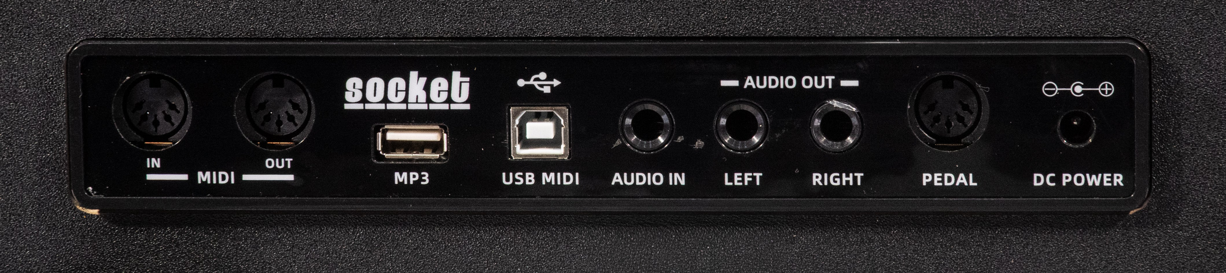 Rückseite eines Geräts mit MIDI-, USB-, Audio- und Stromeingängen auf schwarzem Hintergrund.