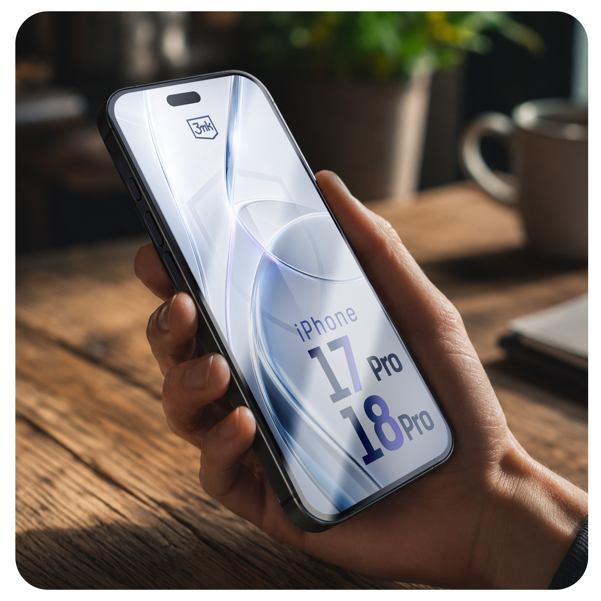 Ręka trzyma smartfon z napisem 'iPhone 17 Pro' i '18 Pro' na ekranie, w drewnianym otoczeniu.