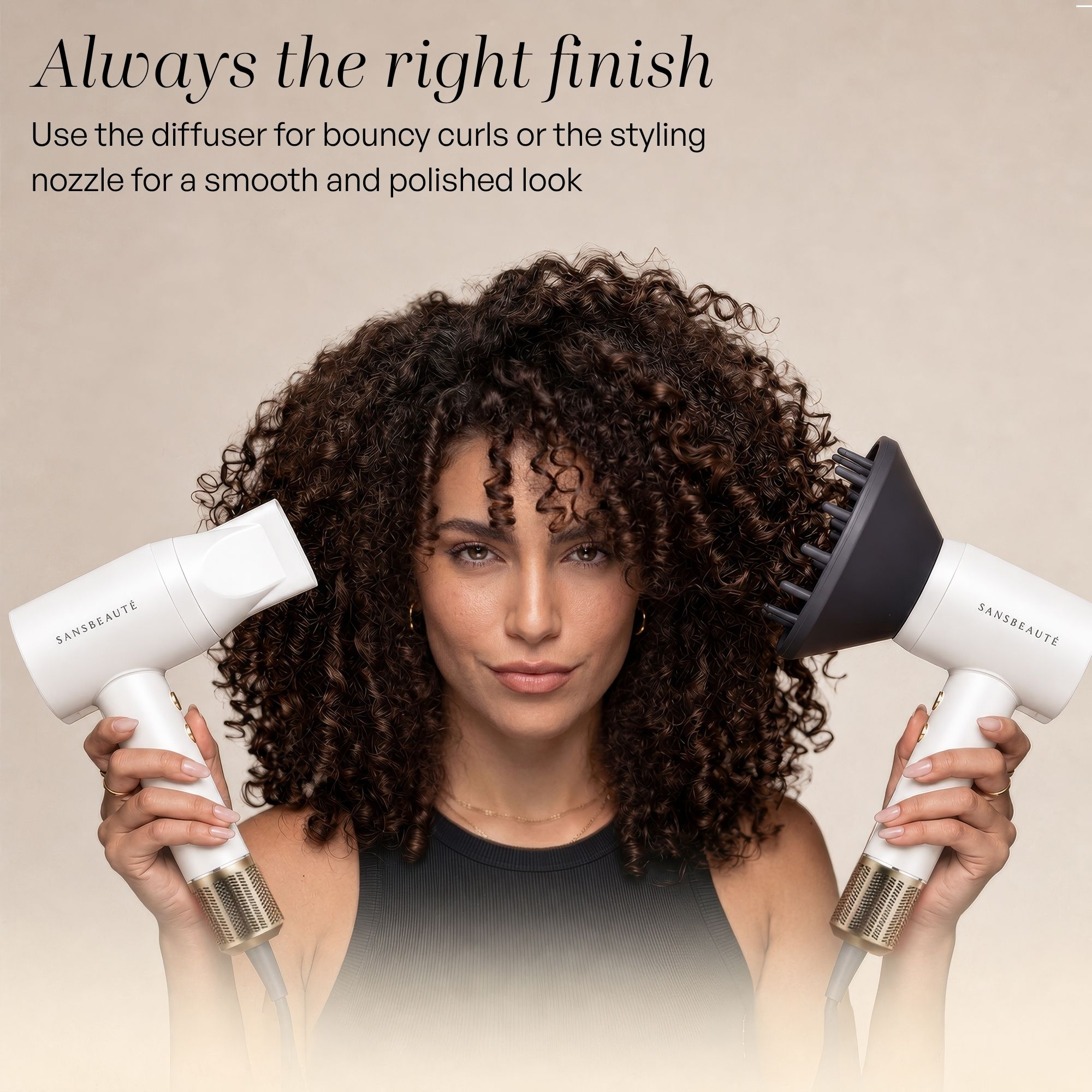 Eine Frau mit dunklen Locken hält zwei weiße Haartrockner, einer mit Düse und einer mit Diffusor.