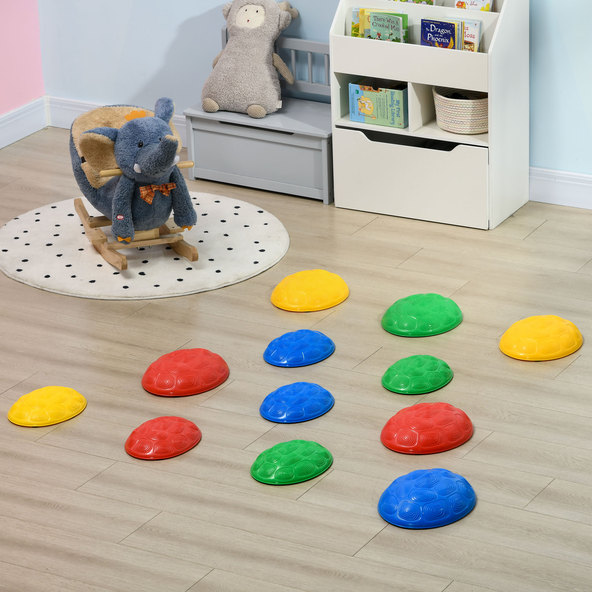 Una sala de juegos con piedras de goma de colores, un balancín de elefante, un banco y una estantería.