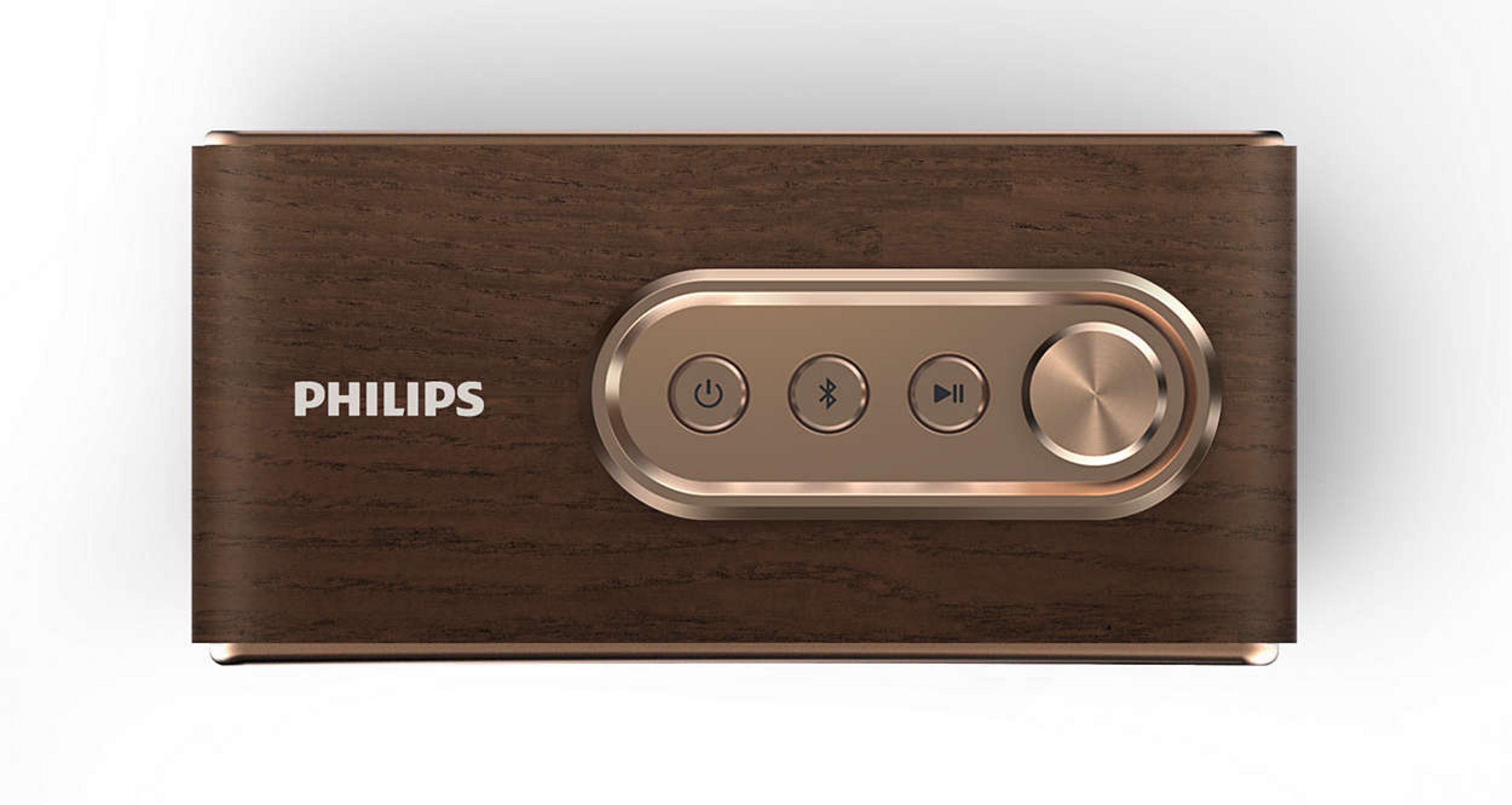 Beyaz arka plan üzerinde pembe altın rengi kontrol düğmelerine ve ses tekerleğine sahip ahşap Philips hoparlör.