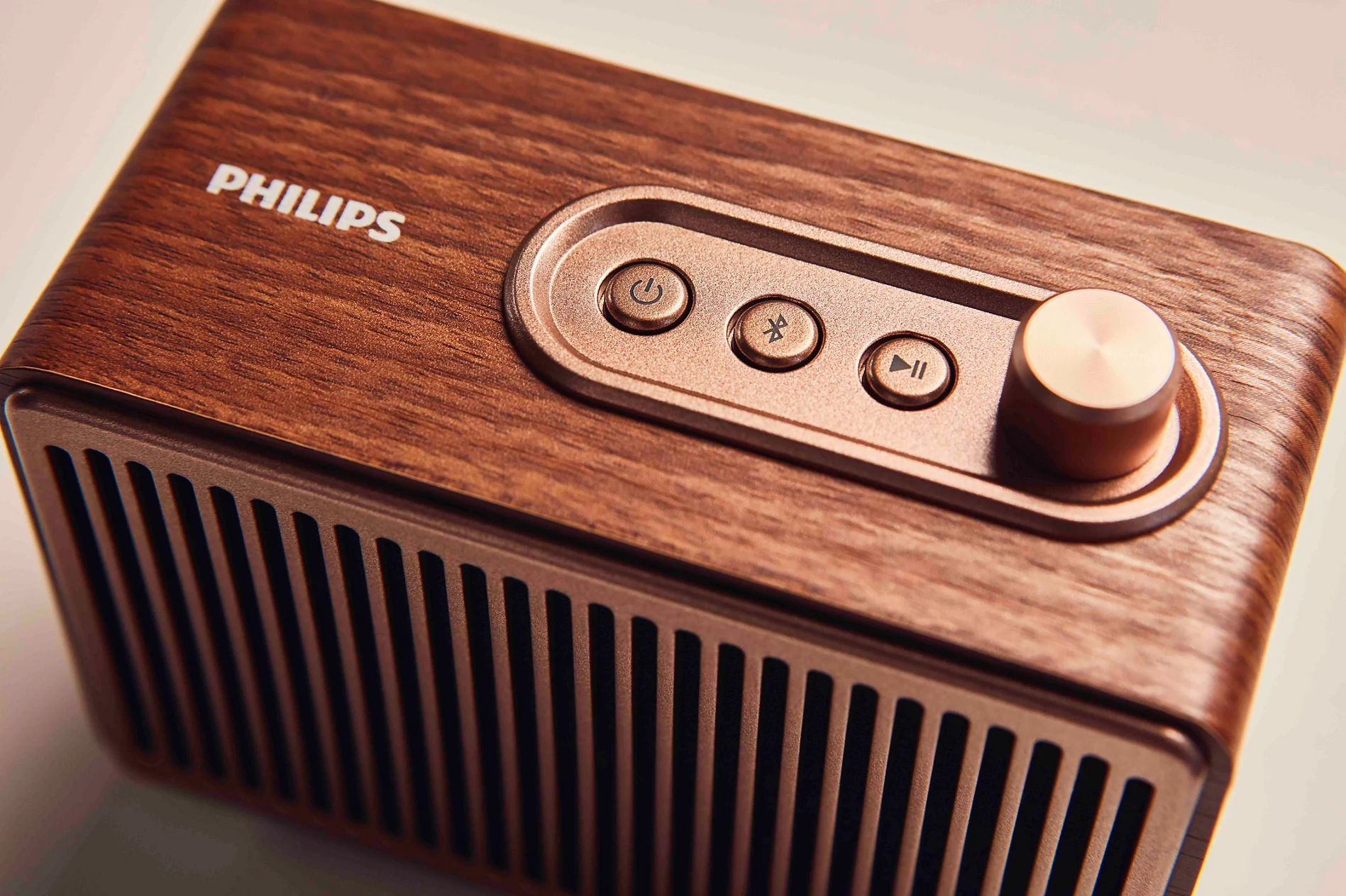 Gül kurusu rengi kontrol düğmelerine sahip ahşap Philips Bluetooth hoparlör.