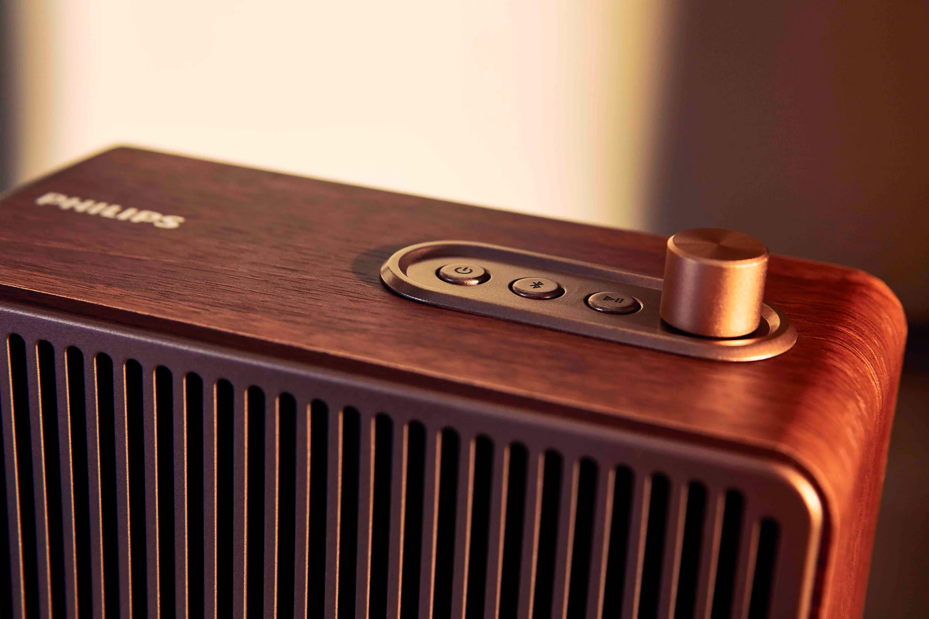 Kontrol düğmeleri ve metal ses düğmesine sahip ahşap Philips hoparlörün üst kısmının yakın planı.